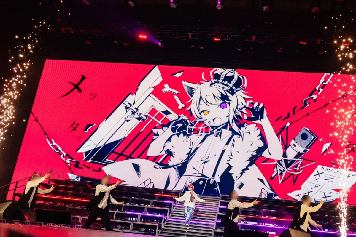 ライブ会場のステージで、巨大な赤いスクリーンに獣耳と王冠をつけたアニメキャラクター