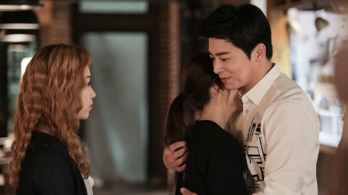 女性を抱きしめる男性と、それを見つめる別の女性