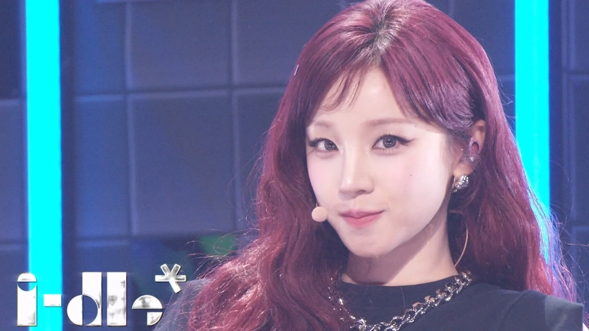 赤いロングヘアの女性アイドルがステージ上でパフォーマンス