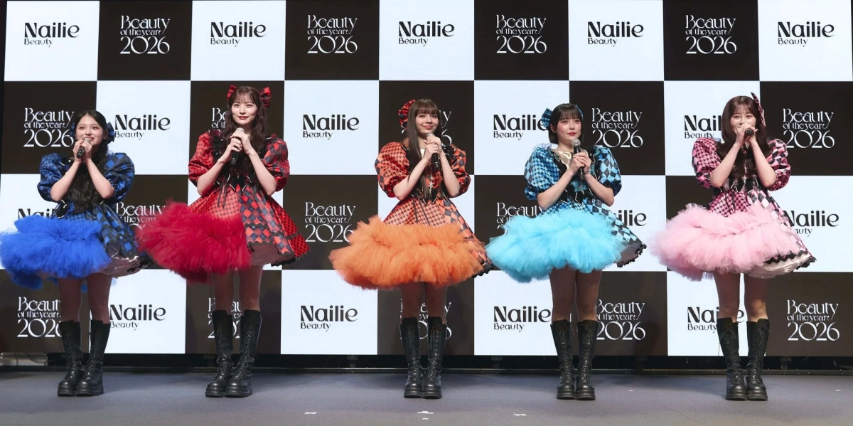 カラフルなフリルドレスとブーツを着用した5人の女性が、マイクを持ってステージに立っています。背景には「Nailie」と「Beauty of the year 2026」のロゴがデザインされており、イベントやパフォーマンスの様子を捉えた一枚です。