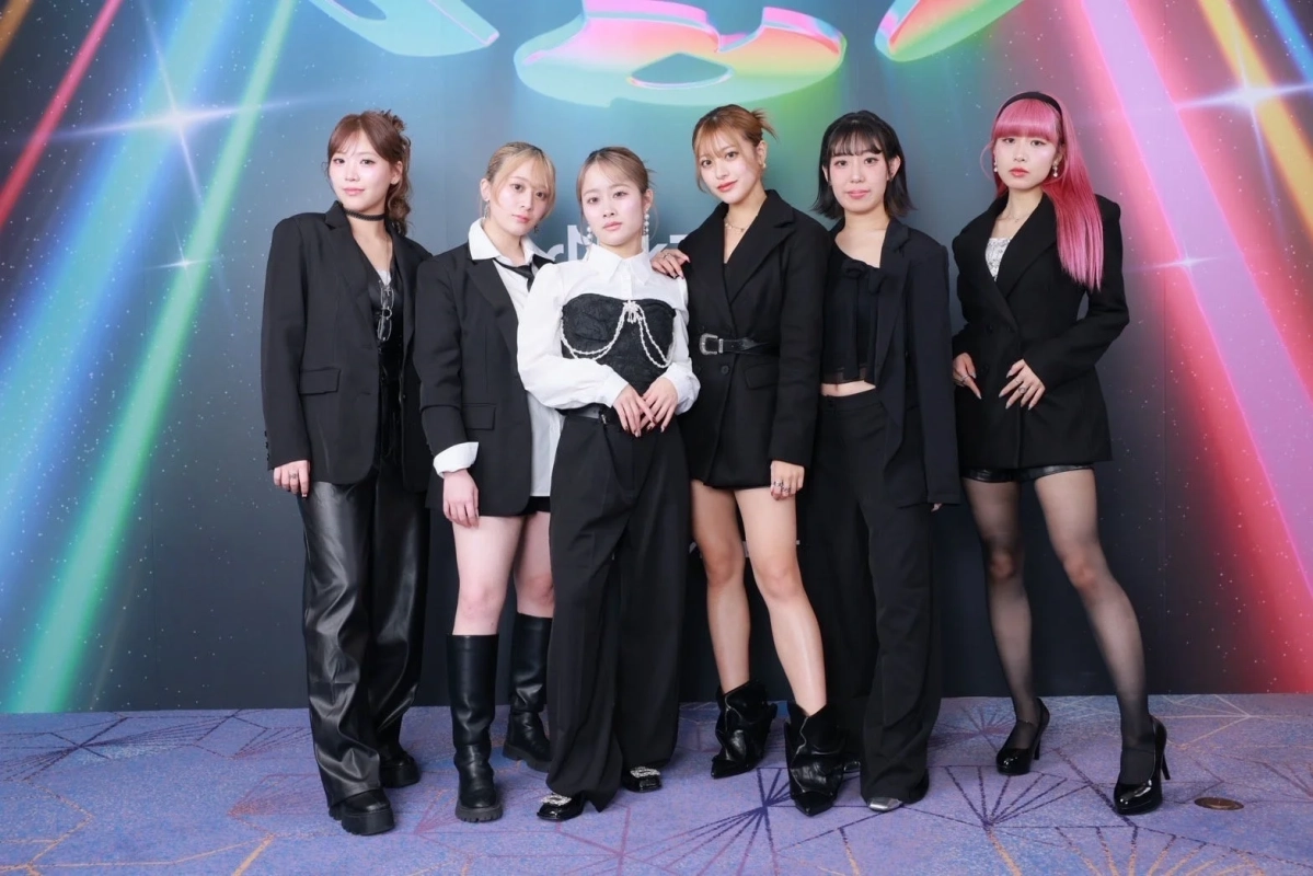 カラフルな光の背景の前でポーズをとる6人の若い女性グループ