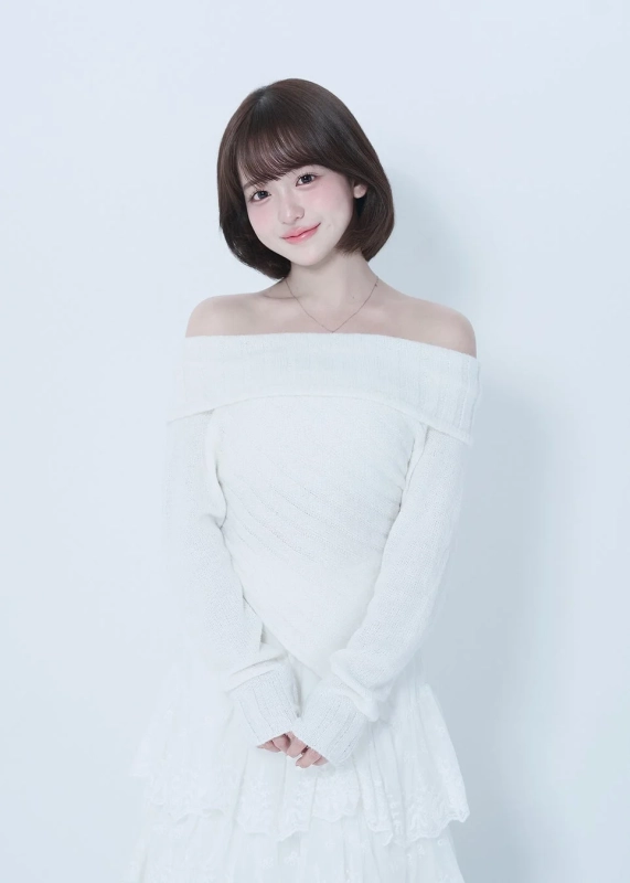 白いオフショルダーのセーターとレースのスカートを身につけたショートヘアの若い女性