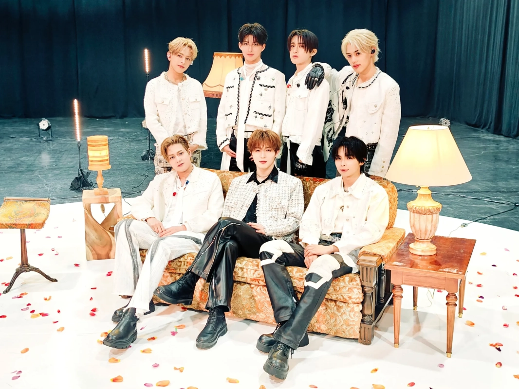 白い衣装を身につけ、スタジオでポーズをとる7人の男性アイドルグループTAGRIGHT