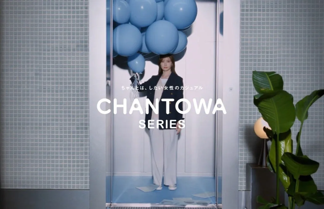 青い風船を手に持った女性がエレベーターの中に立っている広告イメージ