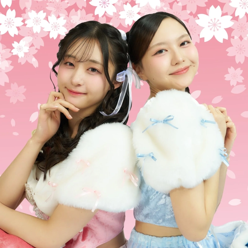 桜柄のピンクの背景の前でポーズをとる二人の若い女性