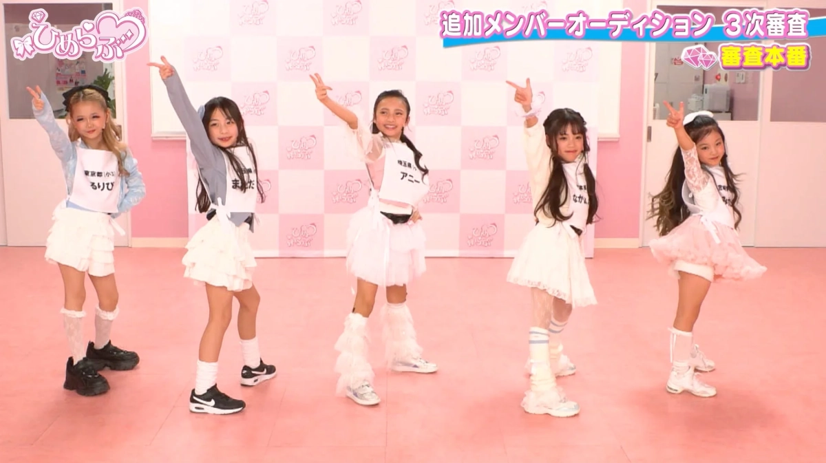 ピンクのステージで、5人の少女たちがアイドルグループの追加メンバーオーディション3次審査に臨んでいる様子