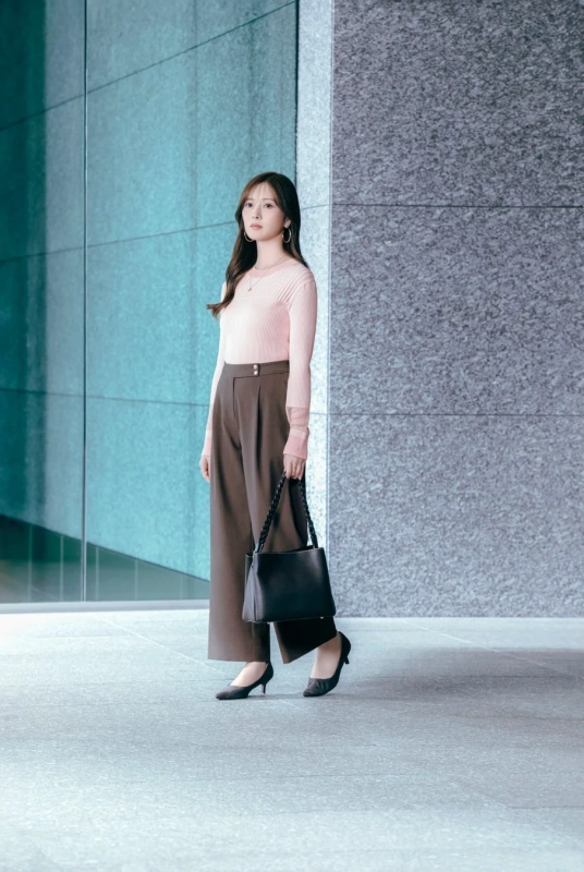 ピンクのニットとブラウンのワイドパンツを着用した女性