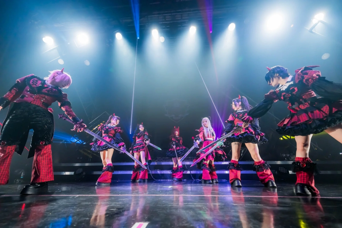 赤と黒のゴシック風衣装を身につけ、剣を持つ7人のパフォーマー