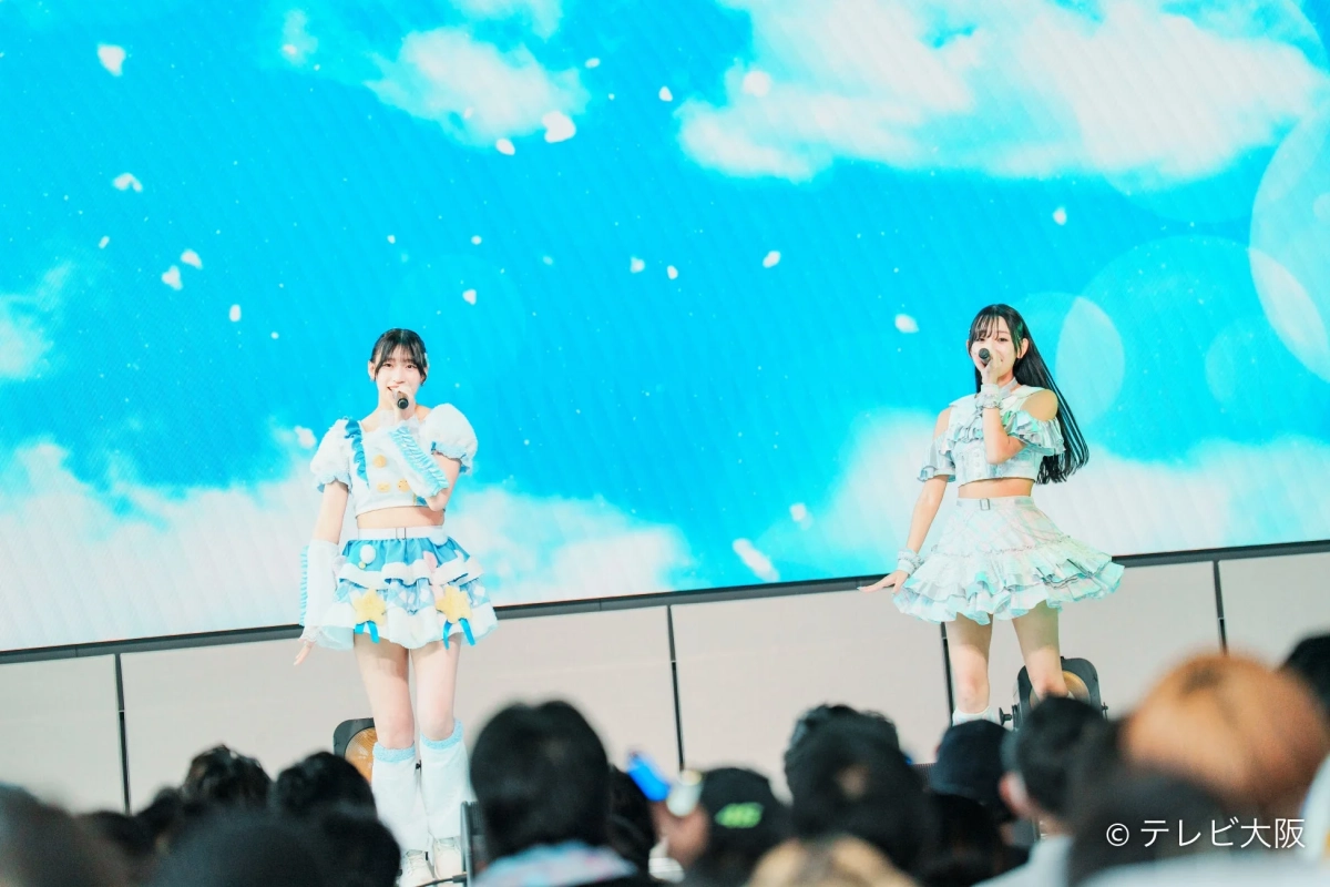 2人のアイドルがステージで歌を披露する様子