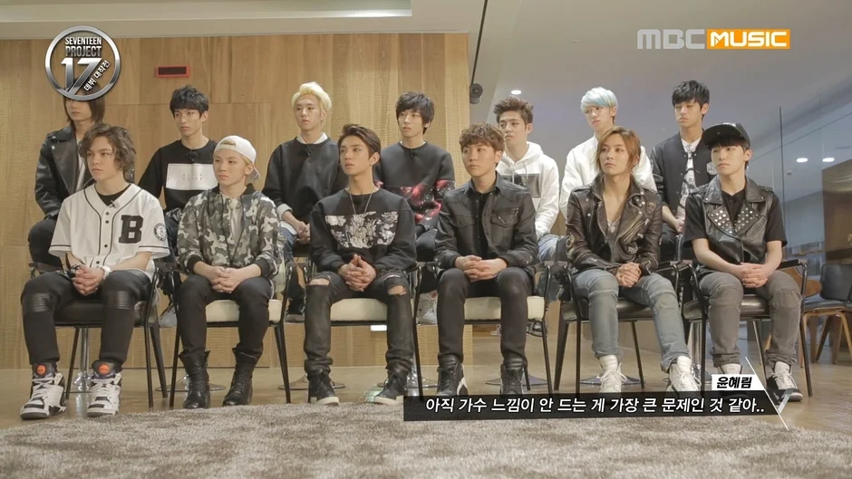 K-POPグループSEVENTEENのメンバーと思われる多数の若い男性が椅子に座っている様子