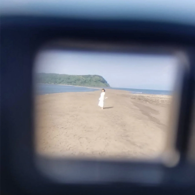 白いドレスの女性が砂浜を歩く海辺の風景