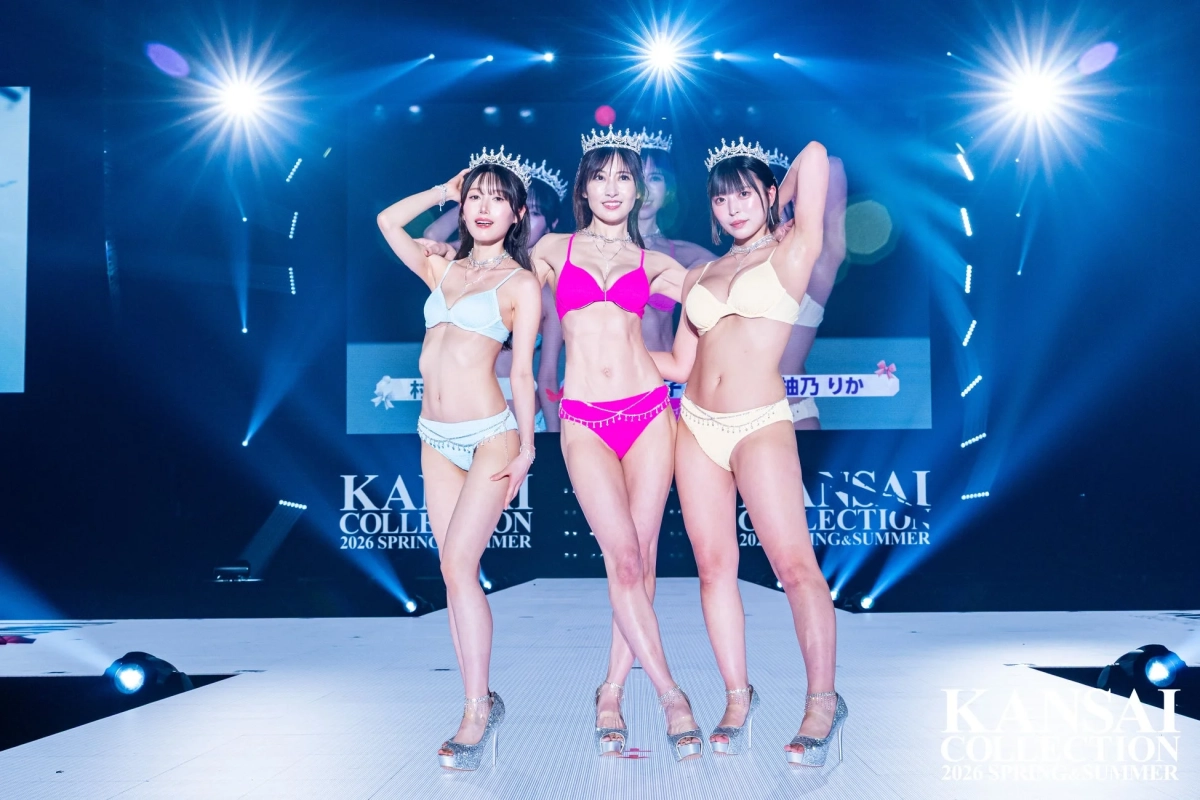 ビキニ姿の3人の女性モデルがティアラを身につけ、スポットライトを浴びながらポーズ