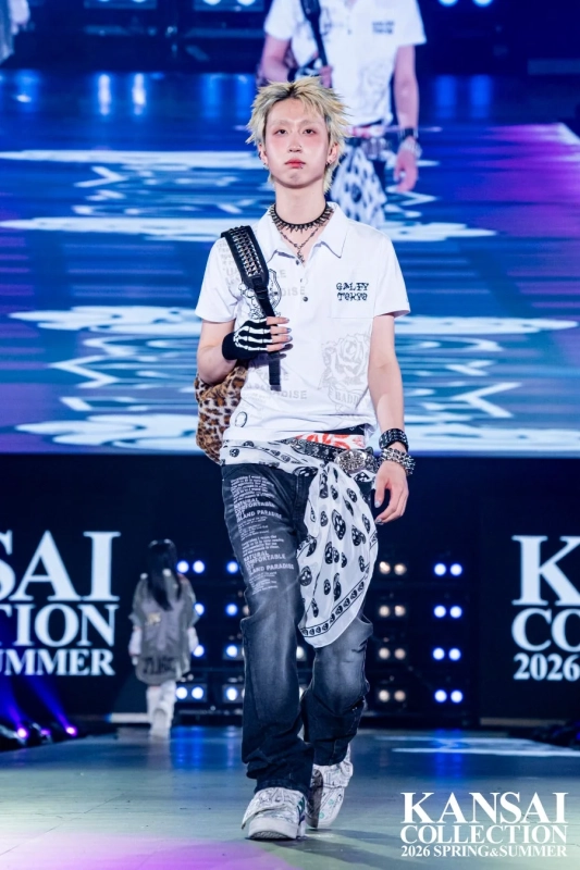 金髪のモデルが、顔にピアスをつけ、パンク調の衣装でランウェイを歩いています