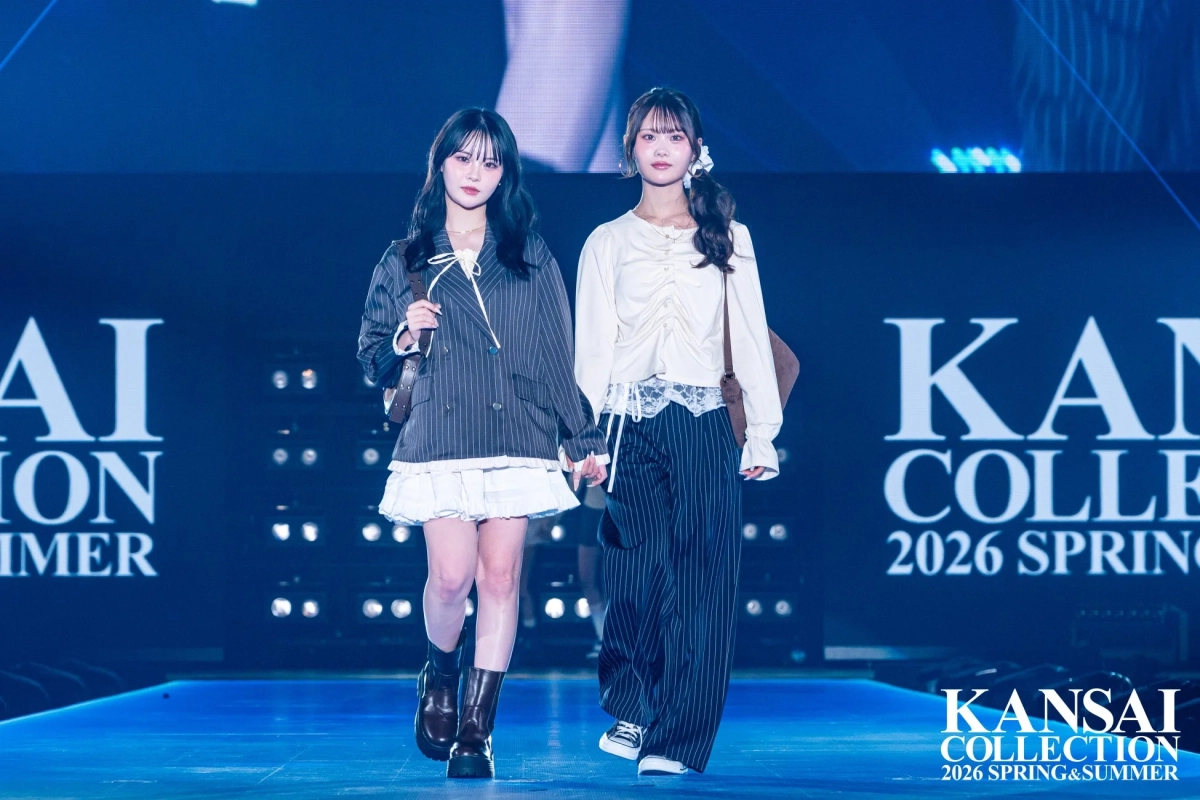 ストライプ柄のジャケットとパンツ、白いフリルスカートとブーツを合わせたトレンド感のあるカジュアルファッションを披露する二人の女性モデル