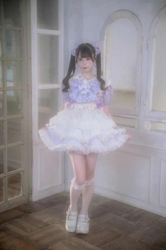 紫と白のフリルが特徴的なドレスを着用し、ツインテールにリボンを飾った女性の全身ポートレート。