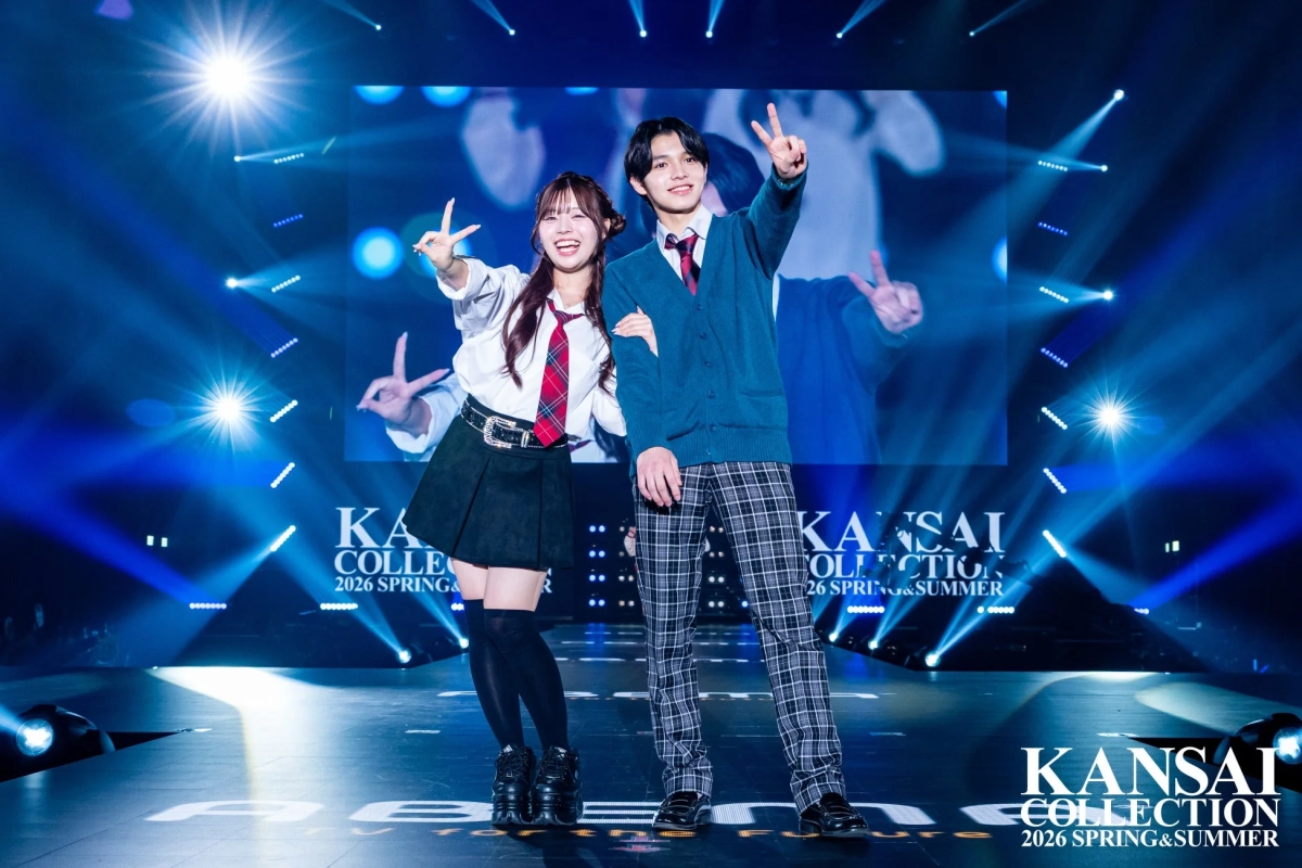 学生服風の衣装を着た男女2人のモデルが笑顔でピースサインをしています