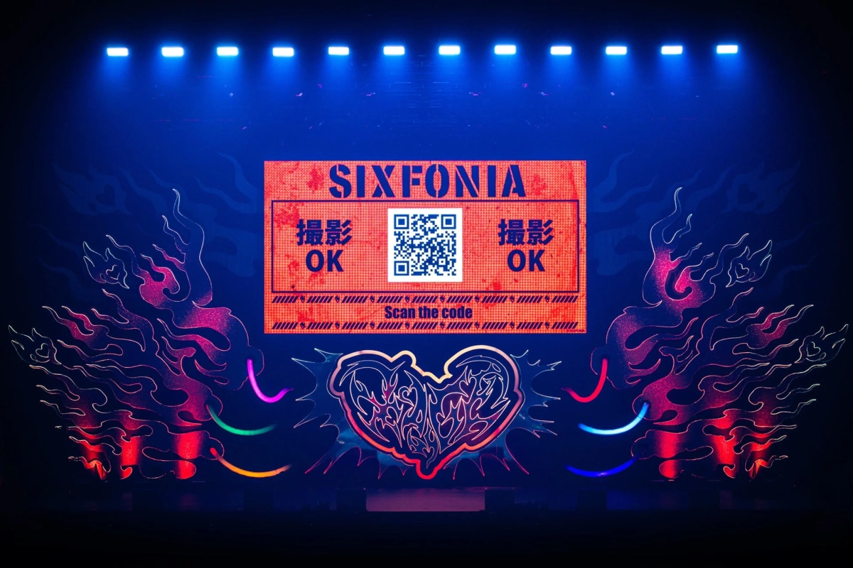 ステージ上の大型スクリーンに「SIXFONIA」のロゴ、撮影許可を示す「撮影 OK」の文字、QRコードが表示されています