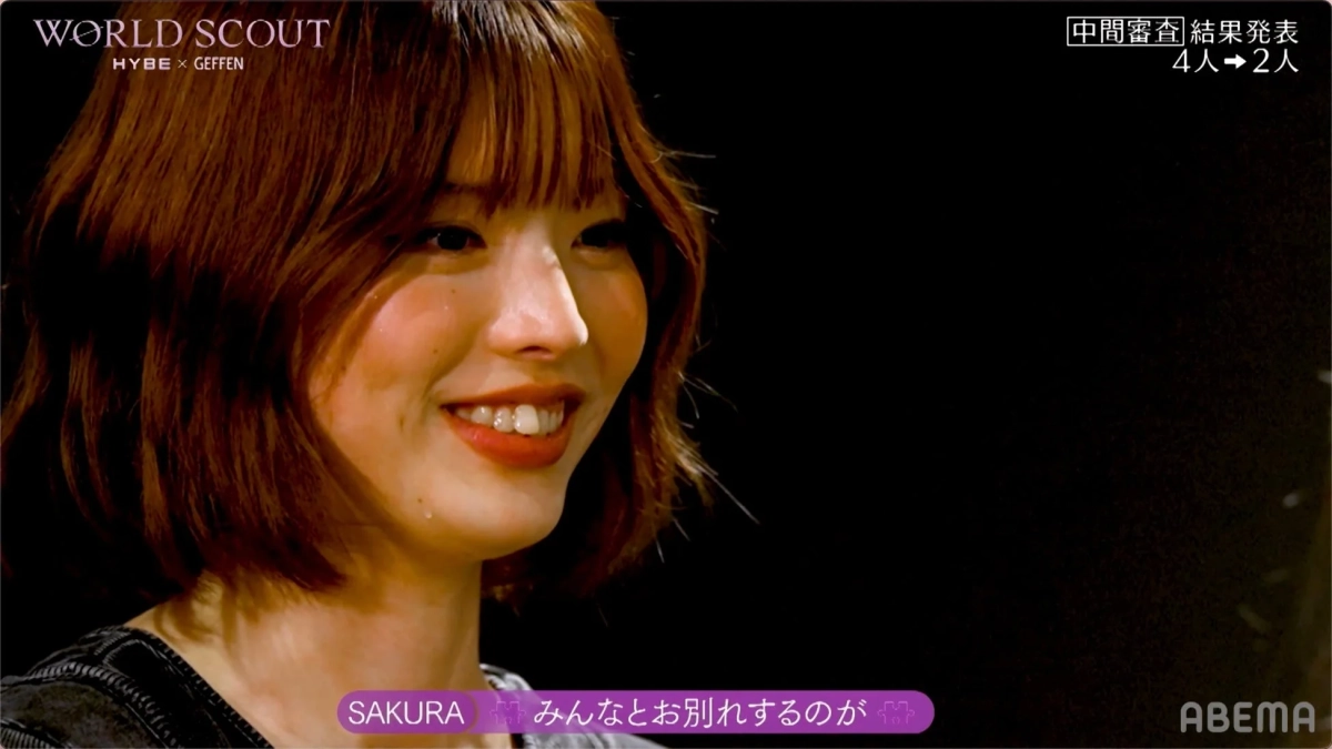 中間審査結果発表の場面で、SAKURAと思われる女性が涙を流しながらも笑顔を見せ、「みんなとお別れするのが」と語っている場面です。