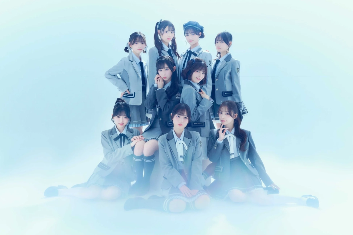 9人の若い女性アイドルグループが、お揃いのグレーの制服を着てポーズをとっている集合写真です。ピラミッド状に配置され、爽やかな青白い背景で清潔感のある印象を与えています。