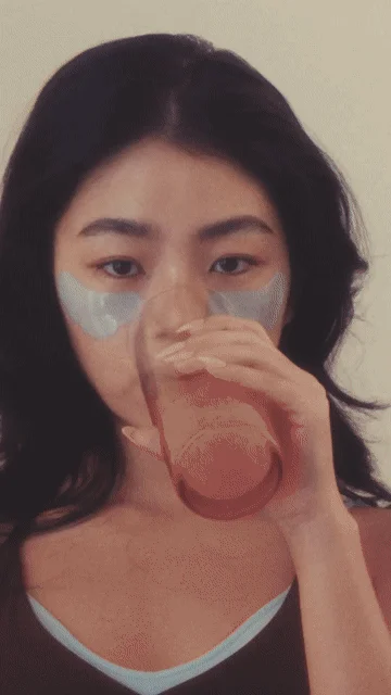 アイパッチをつけた女性が飲み物を飲む