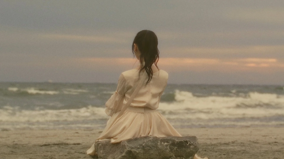 夕暮れのビーチで海を眺める女性