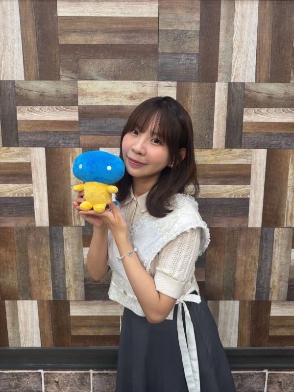 青と黄色の可愛らしいぬいぐるみを両手で持っている古川未鈴さんのポートレート