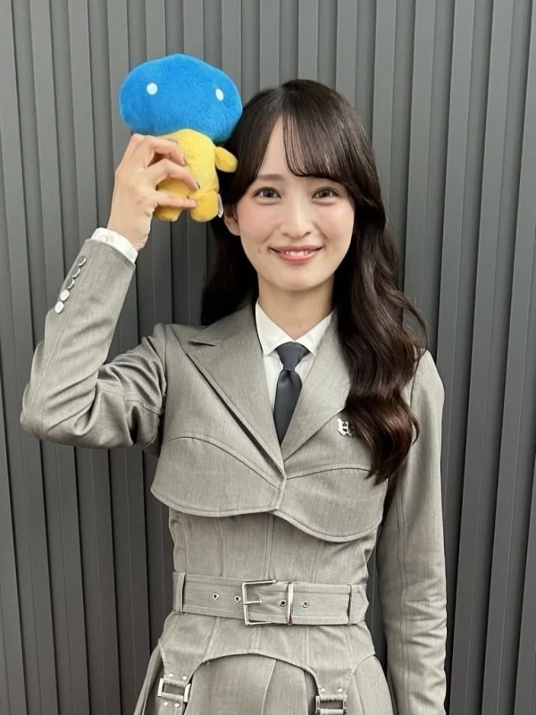 青と黄色の可愛らしいぬいぐるみを頭上に掲げ、笑顔を見せるALLYさんのポートレート