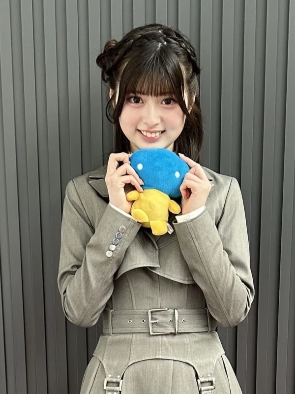 青と黄色の可愛らしいぬいぐるみを持っているHANNAさんのポートレート