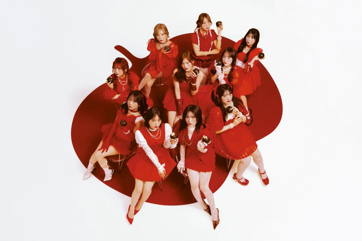 赤い衣装を身につけた11人の女性アイドルグループ