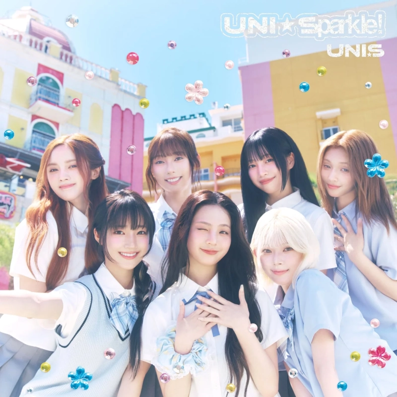 K-POPガールズグループUNISのメンバーたちが、夏らしいカラフルな屋外で制服姿で笑顔を見せている画像