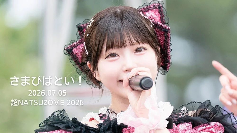 ピンクと黒の華やかな衣装を着た若い女性がマイクを手に歌唱している姿。2026年7月5日の「超NATSUZOME 2026」イベントでのパフォーマンスの様子を捉えた写真です。