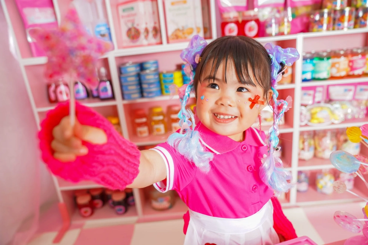 ピンク色の背景に、明るい笑顔の小さな女の子が写っています。