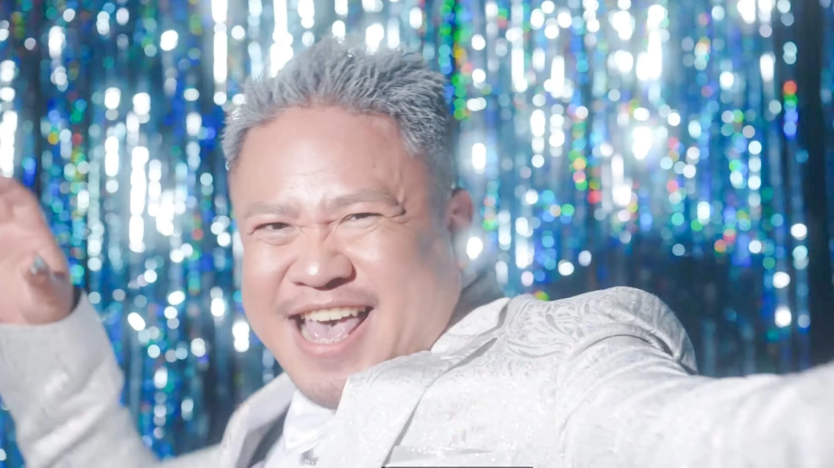 白いスーツの男性が笑顔でポーズ