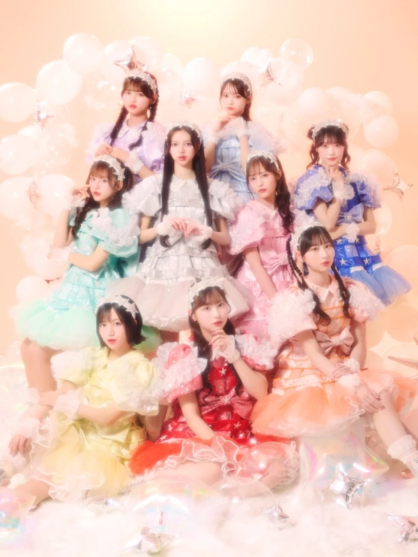 パステルカラーのフリル衣装を着てバルーンと星が飾られた空間で撮影された9人組の女性アイドルグループ