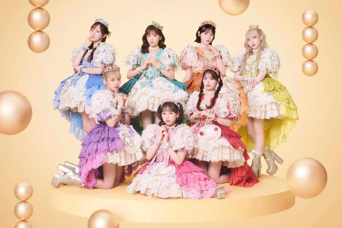 華やかなフリルドレスと王冠を身につけた7人の女性アイドルグループ