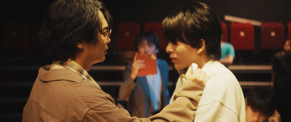 映画のシーン：劇場で会話する男性二人