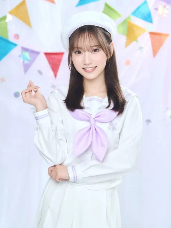 白いセーラー服とベレー帽を着用した若い女性が、カラフルなガーランドを背景に笑顔でポーズをとっています。明るく可愛らしい雰囲気のポートレート写真です。