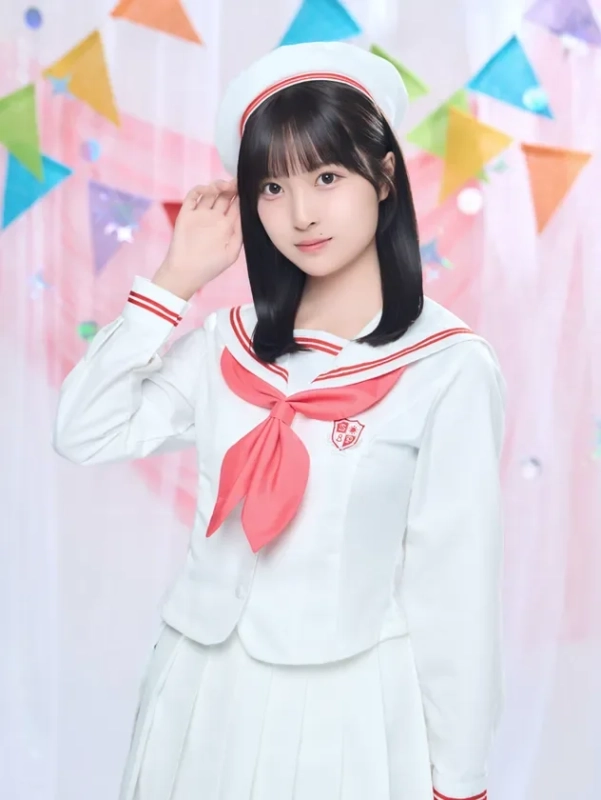 白いセーラー服とベレー帽を着用したアジア系の若い女性が、カラフルなガーランドを背景にポーズをとっています。可愛らしい雰囲気のポートレートです。