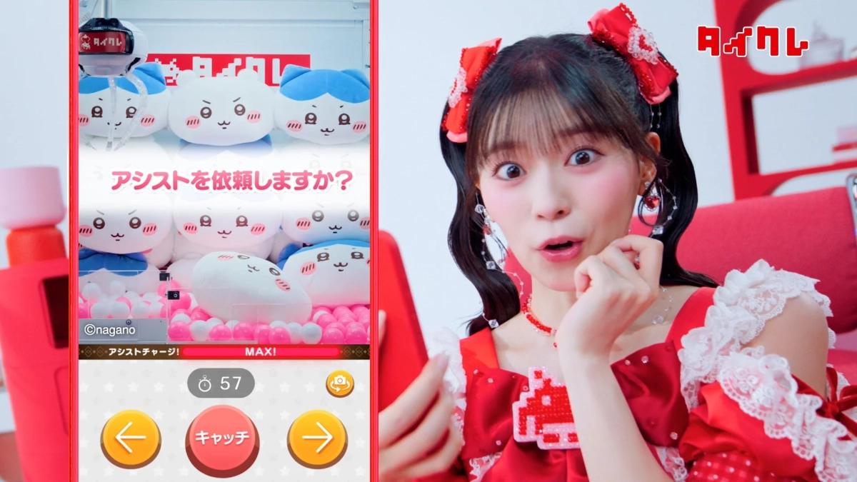 赤いドレスを着た若い女性が、スマートフォンでオンラインクレーンゲームを楽しんでいます。