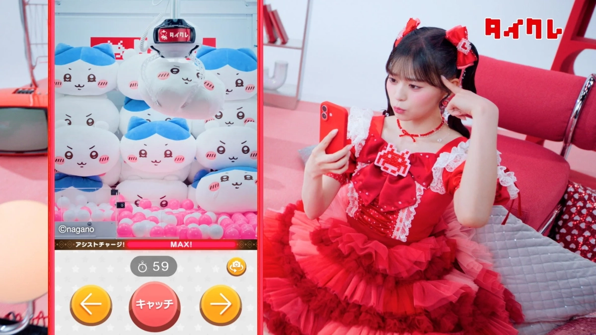 赤いフリルのドレスを着た女性がスマートフォンを手に、オンラインクレーンゲーム「タイクレ」の画面を見ています。